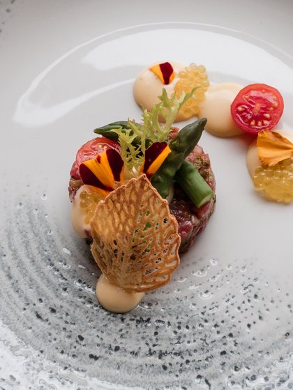 Kunstvoll angerichtetes Gourmet-Gericht mit feinen Beilagen auf einem strukturierten weißen Teller im Hotel Vier Jahreszeiten am Schluchsee.
