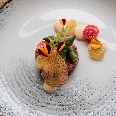 Kunstvoll angerichtetes Gourmet-Gericht mit feinen Beilagen auf einem strukturierten weißen Teller im Hotel Vier Jahreszeiten am Schluchsee.
