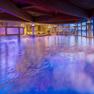 Der stimmungsvoll beleuchtete Innenpool des Hotels Vier Jahreszeiten mit Blick in den verschneiten Garten.