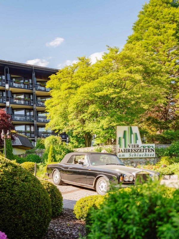 Die blühende, sommerliche Hotelauffahrt des Hotels Vier Jahreszeiten am Schluchsee mit gepflegten Grünanlagen.