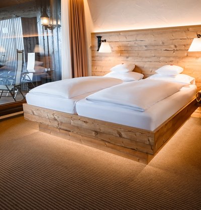 Rustikales Doppelbett mit indirekter Beleuchtung im Hotel Vier Jahreszeiten am Schluchsee.
