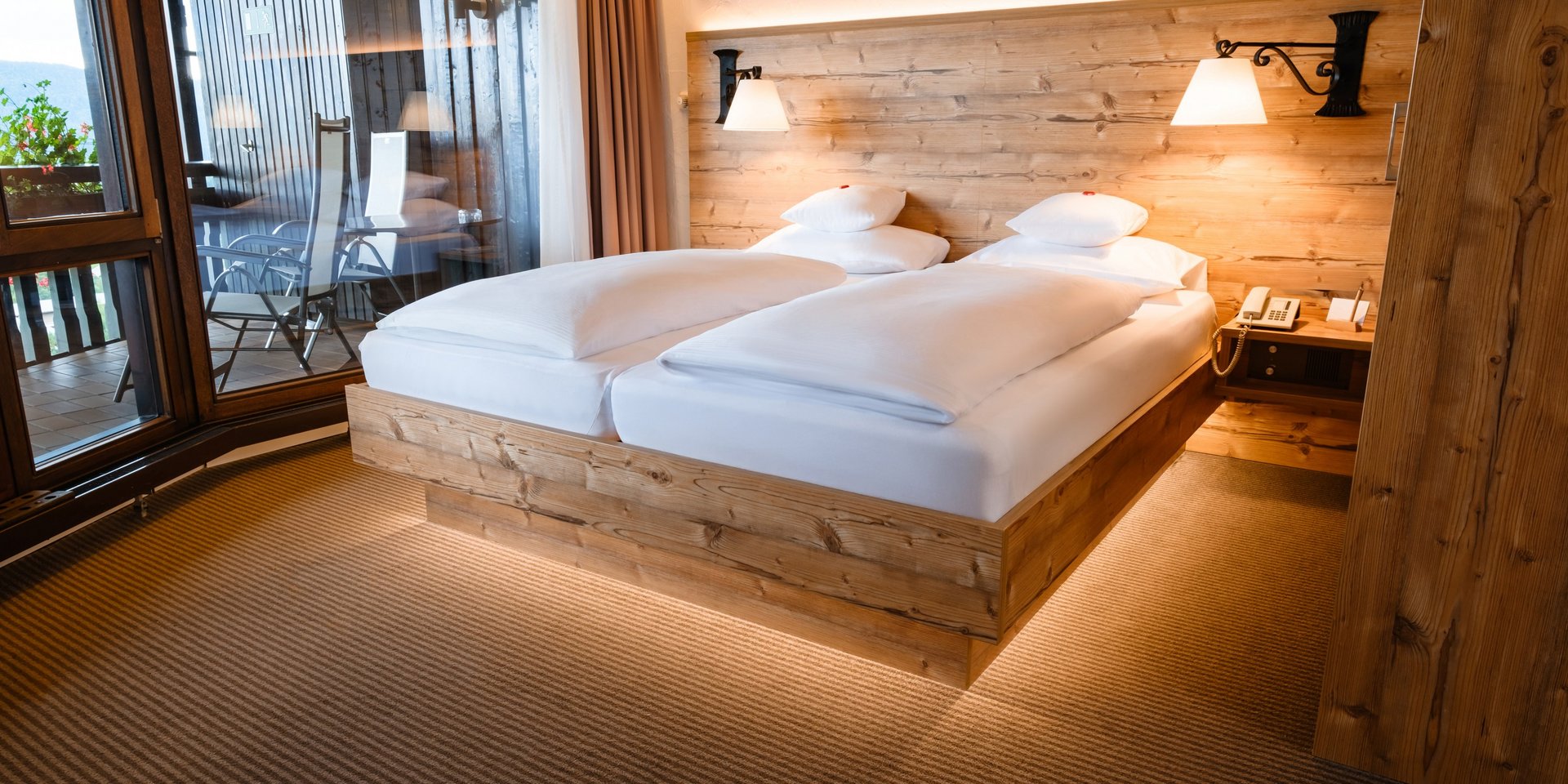 Rustikales Doppelbett mit indirekter Beleuchtung im Hotel Vier Jahreszeiten am Schluchsee.