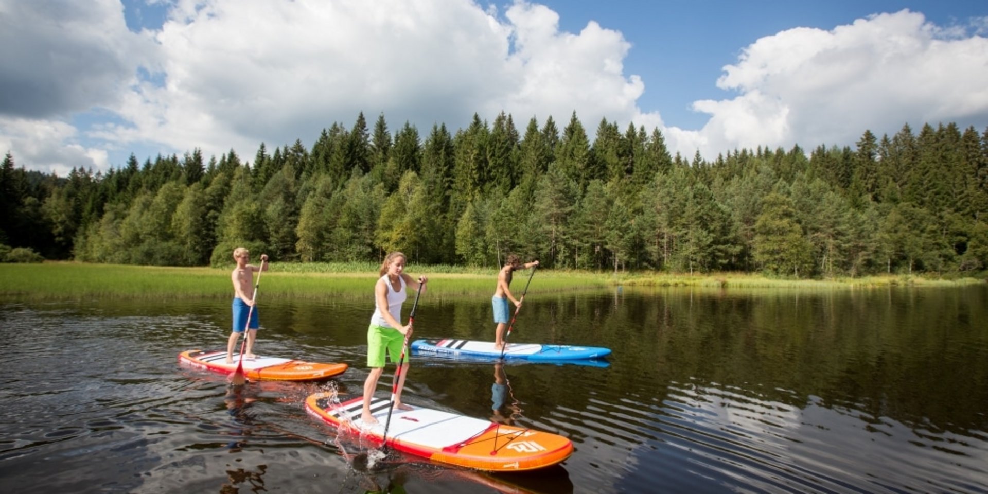 Drei Personen paddeln auf Stand-up-Paddle-Boards am Windgefällweiher.
