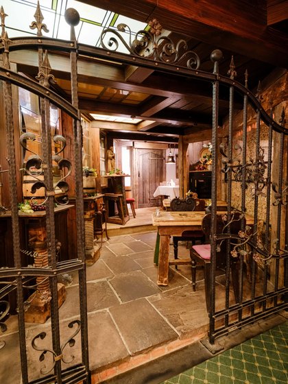 Blick durch ein schmiedeeisernes Gitter in das gemütliche und weinumrankte Weinkabinett.