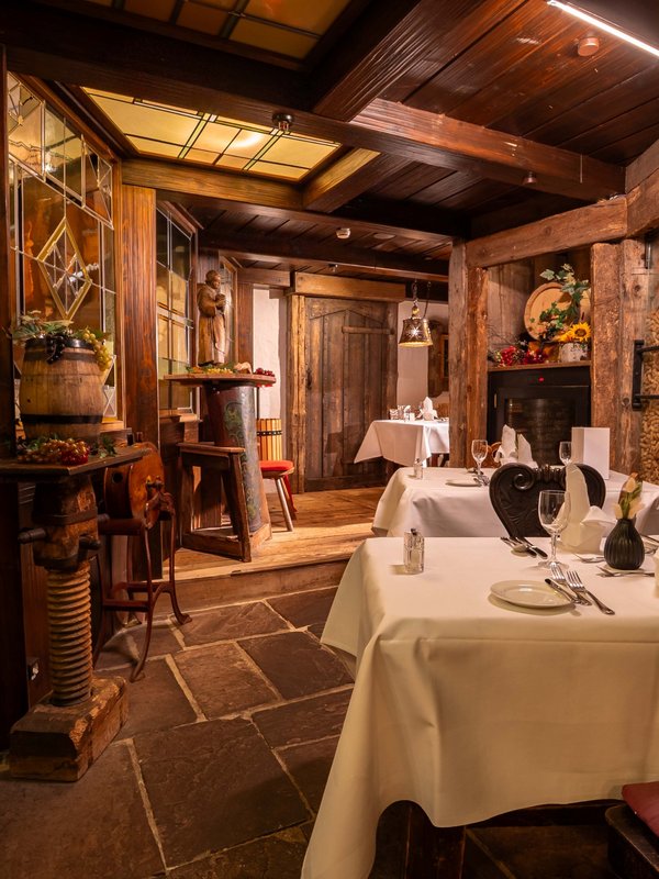 Exklusives Ambiente im Weinkabinett mit festlich gedecktem Tisch und rustikalen Weinregalen.