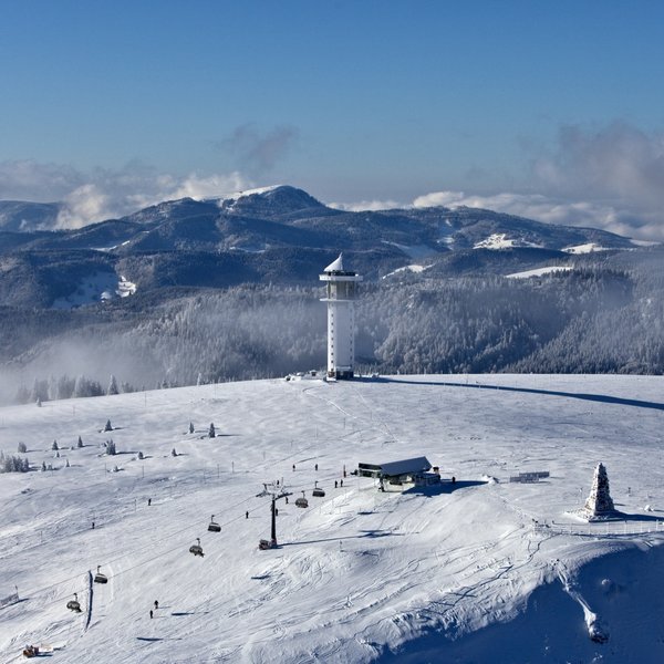 Luftbild der verschneiten Landschaft und Skipisten am Feldberg im Winter.