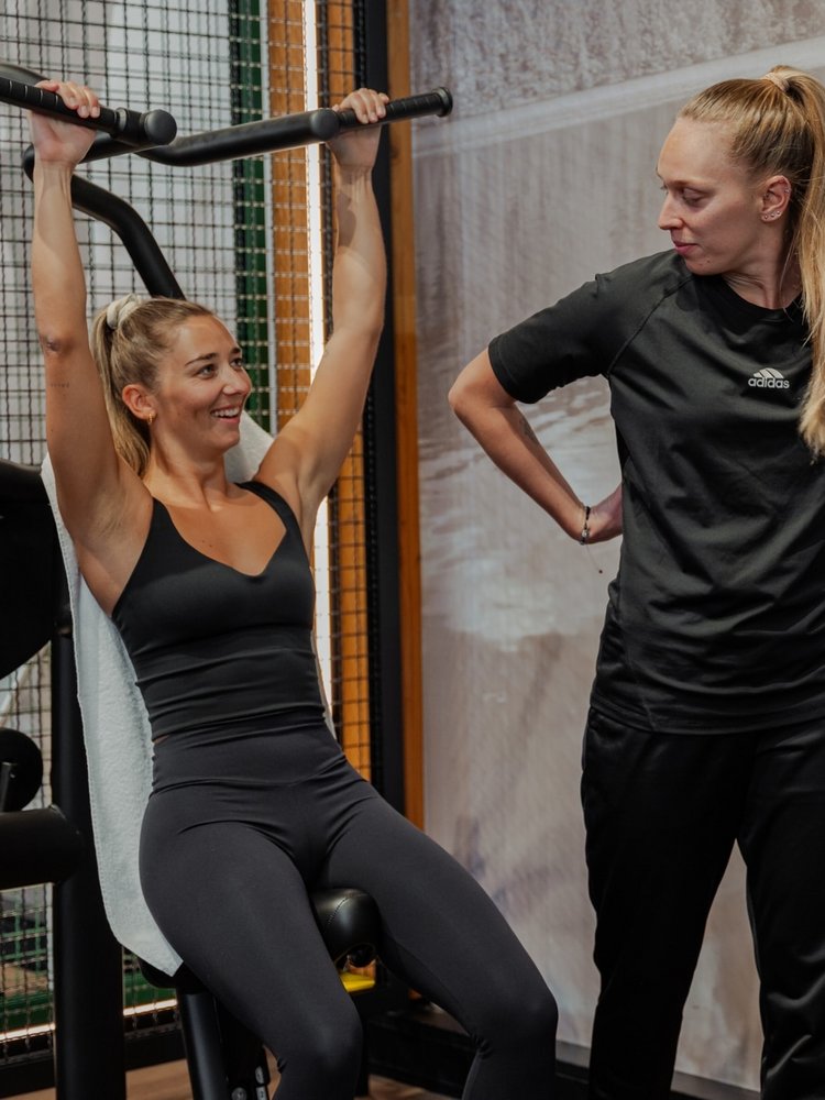 Eine Frau trainiert konzentriert an einem modernen Fitnessgerät im hoteleigenen Gym des Hotels Vier Jahreszeiten.