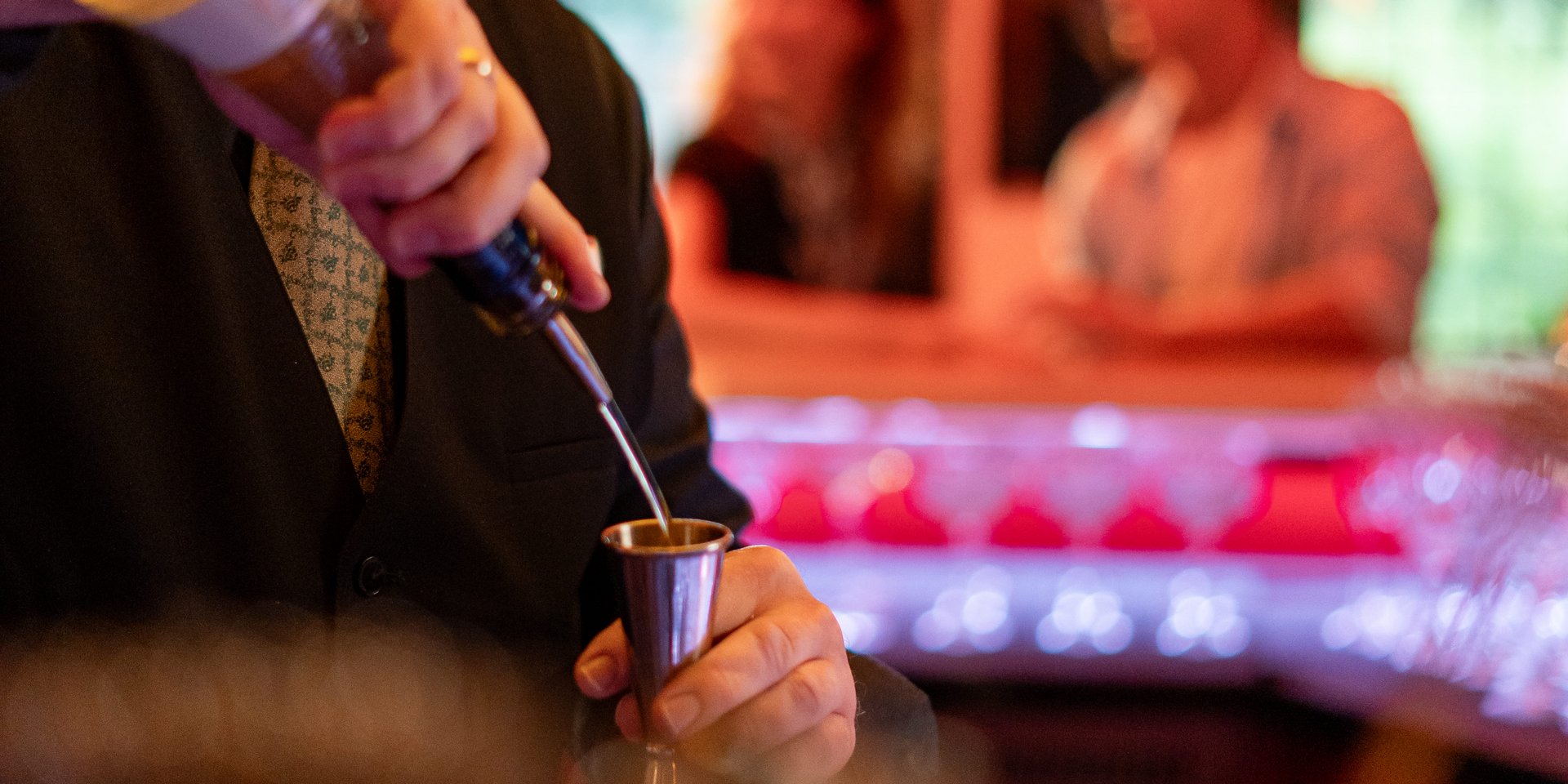 Ein erfahrener Barkeeper mixt professionell Cocktails an der beleuchteten Hotelbar am Schluchsee.