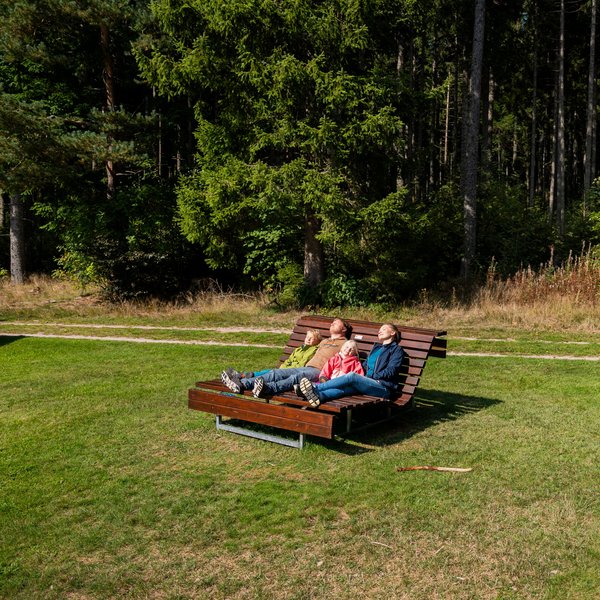 Entspannung pur: Eine Familie ruht sich auf einer hölzernen Wellenliege auf einer grünen Wiese am Hotel Vier Jahreszeiten am Schluchsee aus.