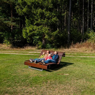 Entspannung pur: Eine Familie ruht sich auf einer hölzernen Wellenliege auf einer grünen Wiese am Hotel Vier Jahreszeiten am Schluchsee aus.