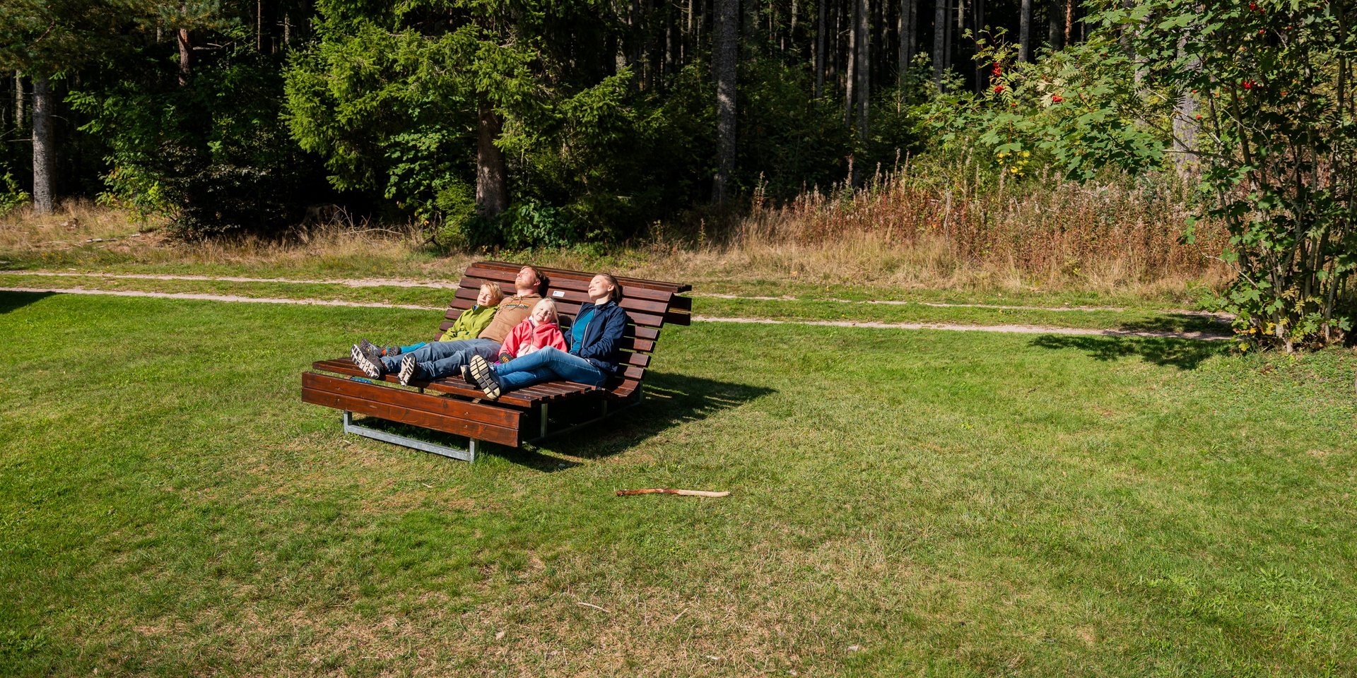 Entspannung pur: Eine Familie ruht sich auf einer hölzernen Wellenliege auf einer grünen Wiese am Hotel Vier Jahreszeiten am Schluchsee aus.