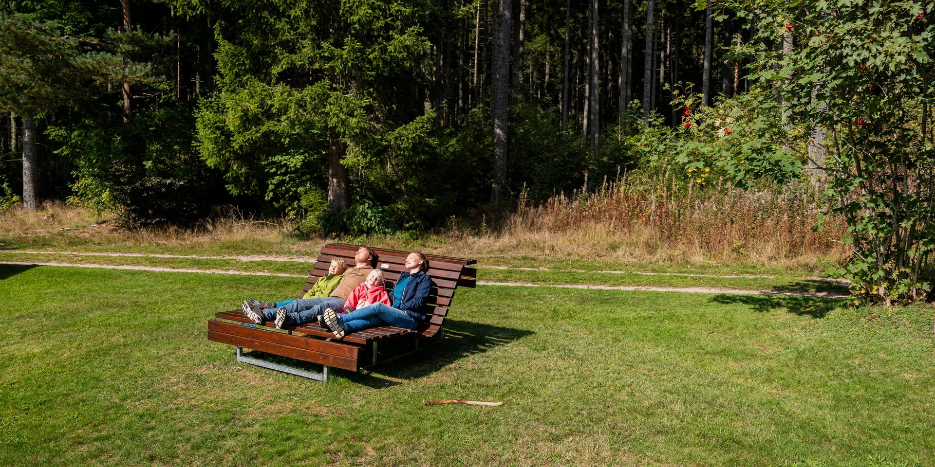 Entspannung pur: Eine Familie ruht sich auf einer hölzernen Wellenliege auf einer grünen Wiese am Hotel Vier Jahreszeiten am Schluchsee aus.