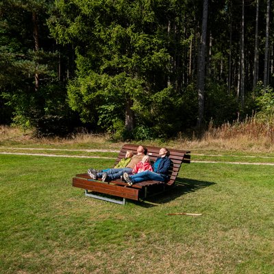 Entspannung pur: Eine Familie ruht sich auf einer hölzernen Wellenliege auf einer grünen Wiese am Hotel Vier Jahreszeiten am Schluchsee aus.