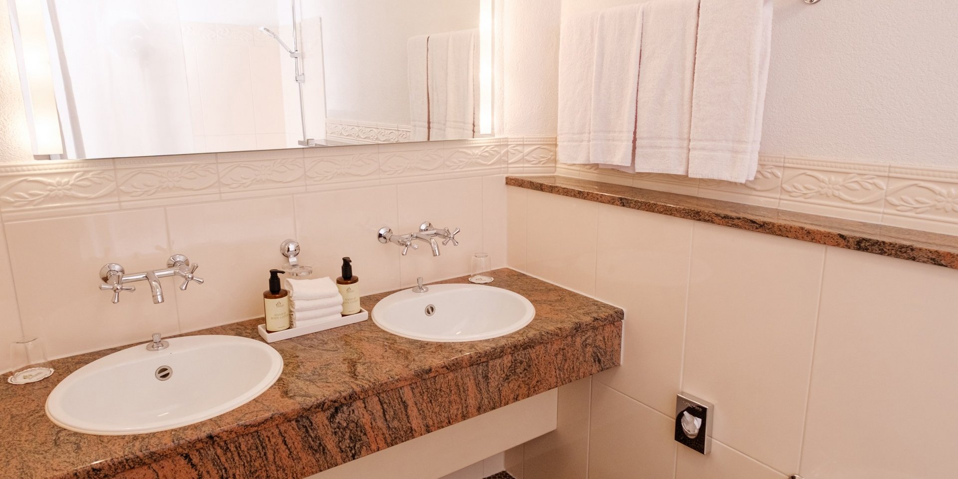 Modernes Badezimmer mit Doppelwaschbecken und großem Spiegel im Hotel Vier Jahreszeiten am Schluchsee.