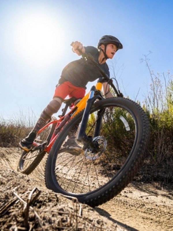 Ein kleiner Radfahrer meistert eine Kurve auf einem staubigen Pfad während eines Bike-Kurses.