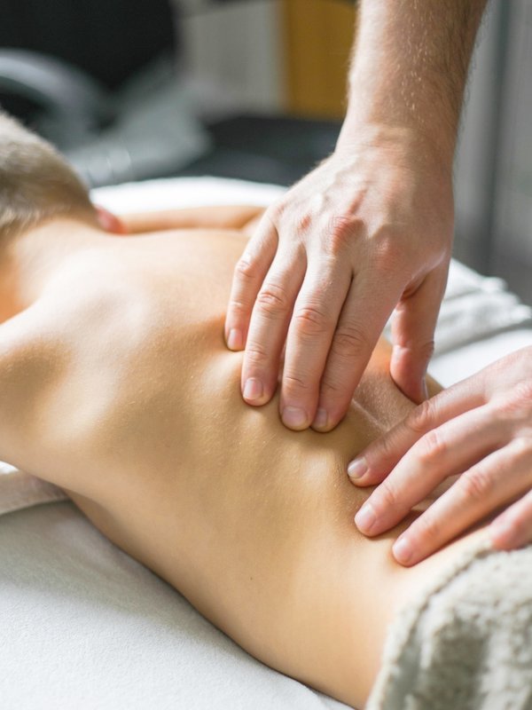 Ein Kind erhält eine sanfte Rückenmassage während einer speziellen Kids-Wellness-Anwendung im Hotel Vier Jahreszeiten am Schluchsee.