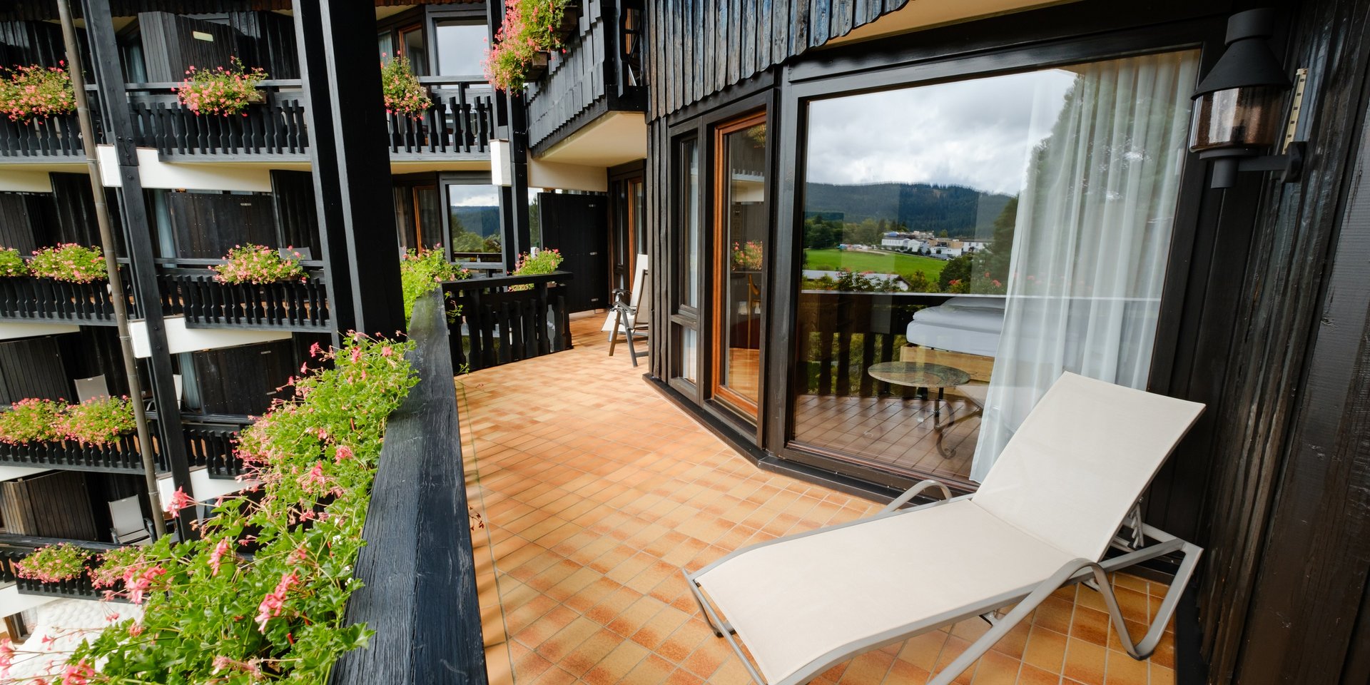 Großzügige Terrasse der Superior Suite Süd mit Sonnenliege und Blick auf die Fassade.