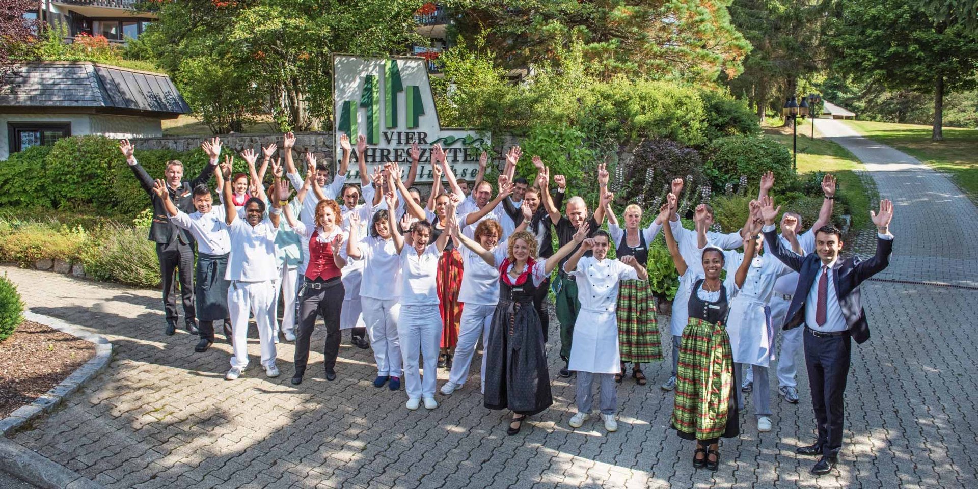 Das gesamte Team des Hotels Vier Jahreszeiten jubelt gemeinsam in der gepflegten Außenanlage unseres Hauses im Schwarzwald.