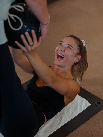 Funktionelles Training: Eine Sportlerin trainiert mit einem Medizinball im Gym.