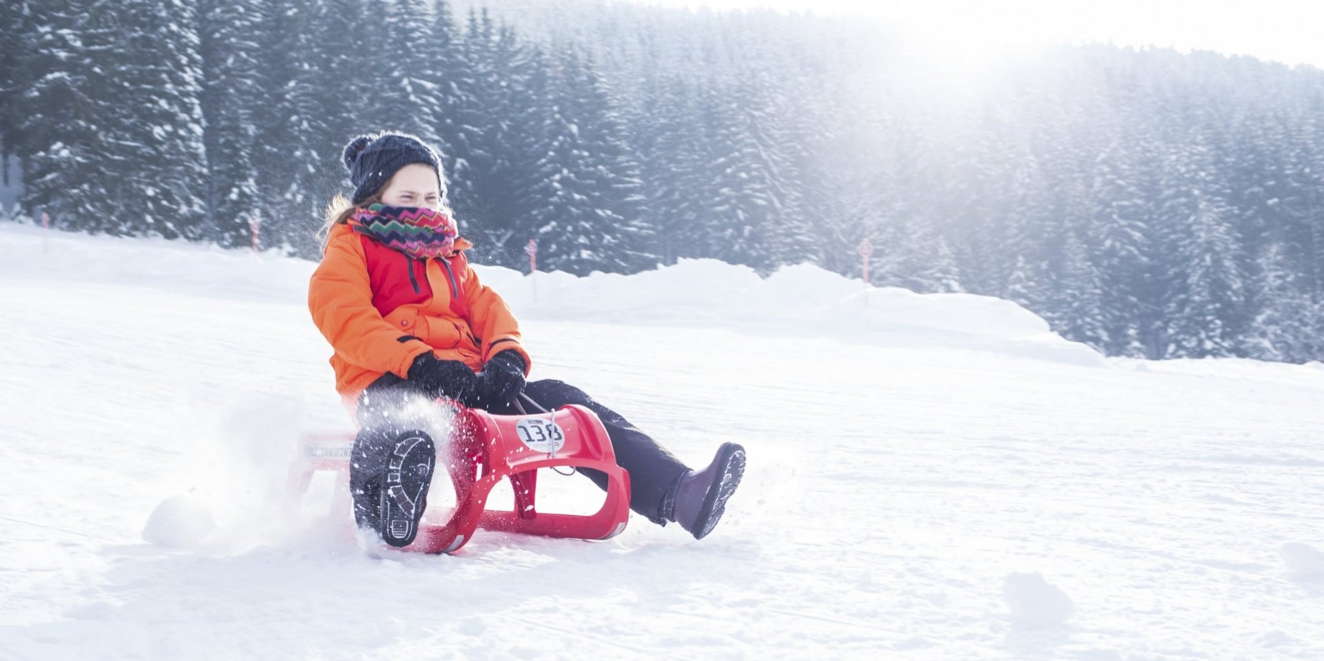 Rasante Schlittenfahrt: Ein Kind rodelt eine schneebedeckte hinunter.