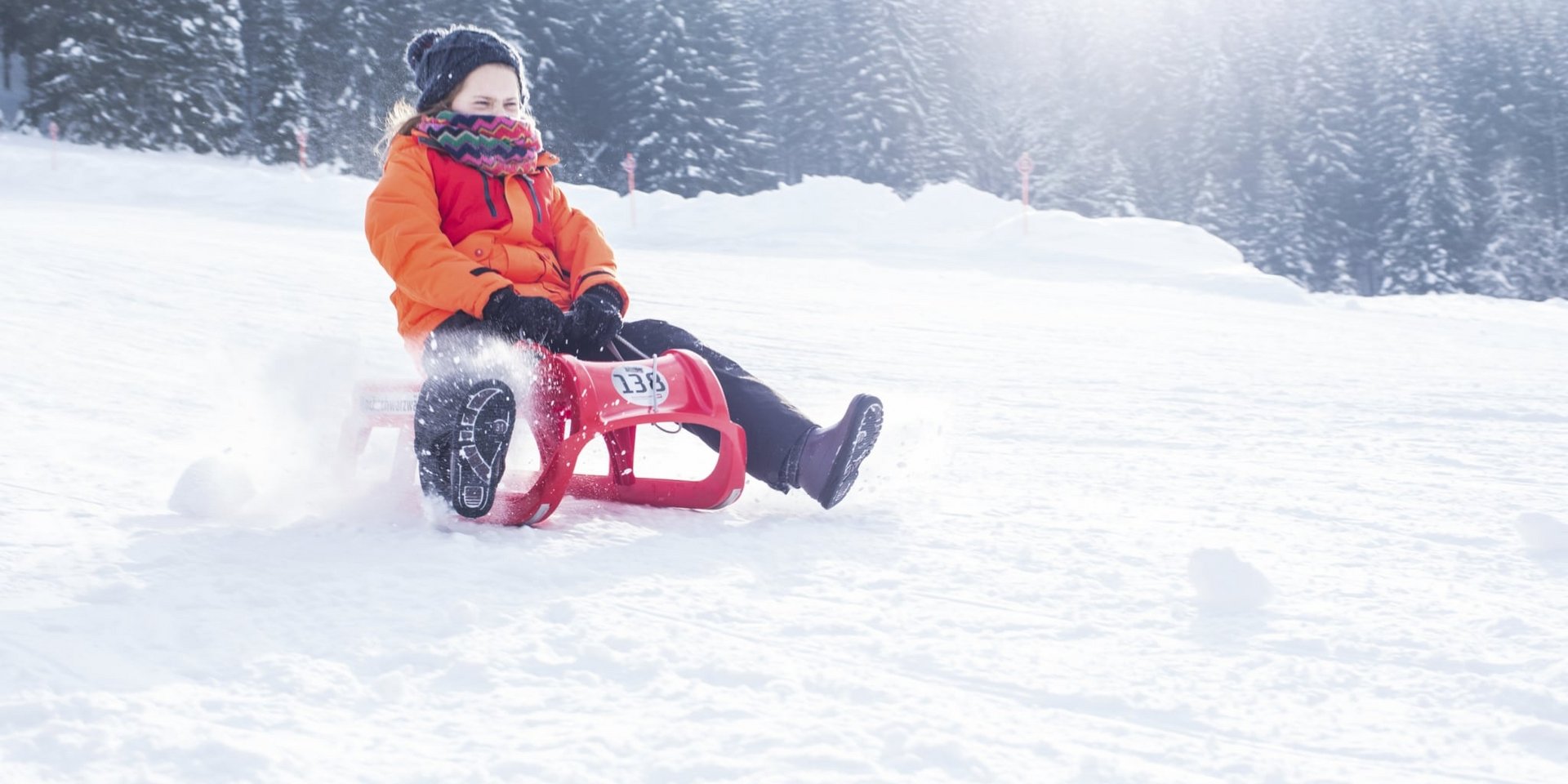 Rasante Schlittenfahrt: Ein Kind rodelt eine schneebedeckte hinunter.