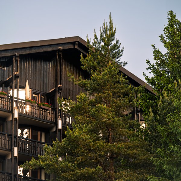 Außenansicht der Hotel-Fassade mit Holzbalkonen, umgeben von Tannen im Schwarzwald.