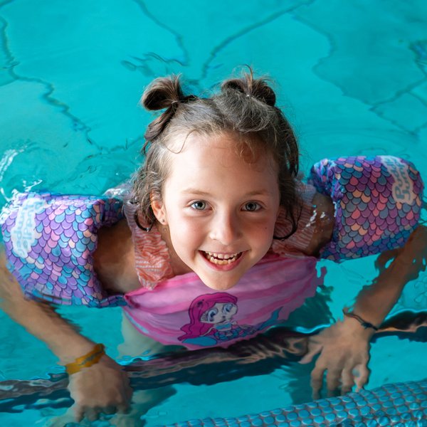 Ein Mädchen lacht vergnügt beim Planschen im Hallenbad des Hotels Vier Jahreszeiten am Schluchsee.