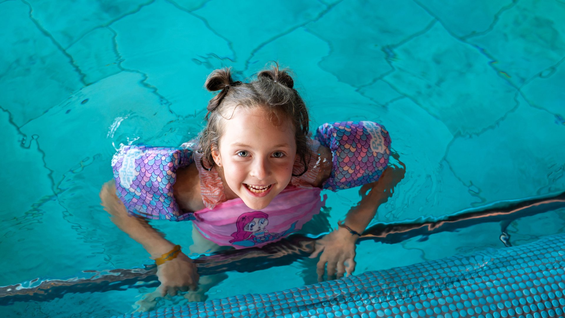 Ein Mädchen lacht vergnügt beim Planschen im Hallenbad des Hotels Vier Jahreszeiten am Schluchsee.
