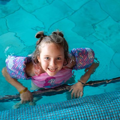Ein Mädchen lacht vergnügt beim Planschen im Hallenbad des Hotels Vier Jahreszeiten am Schluchsee.