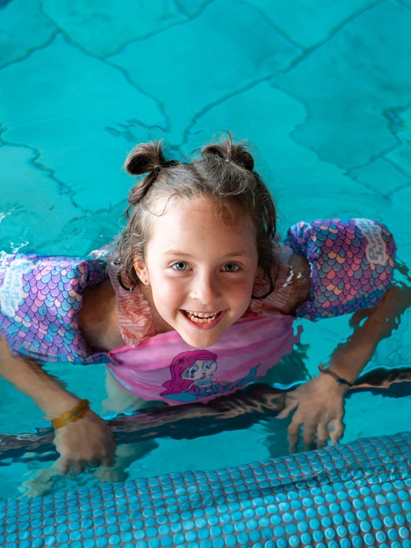 Ein Mädchen lacht vergnügt beim Planschen im Hallenbad des Hotels Vier Jahreszeiten am Schluchsee.