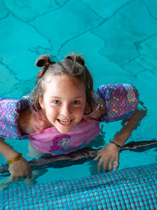 Ein Mädchen lacht vergnügt beim Planschen im Hallenbad des Hotels Vier Jahreszeiten am Schluchsee.