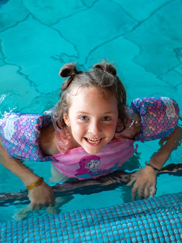 Ein Mädchen lacht vergnügt beim Planschen im Hallenbad des Hotels Vier Jahreszeiten am Schluchsee.