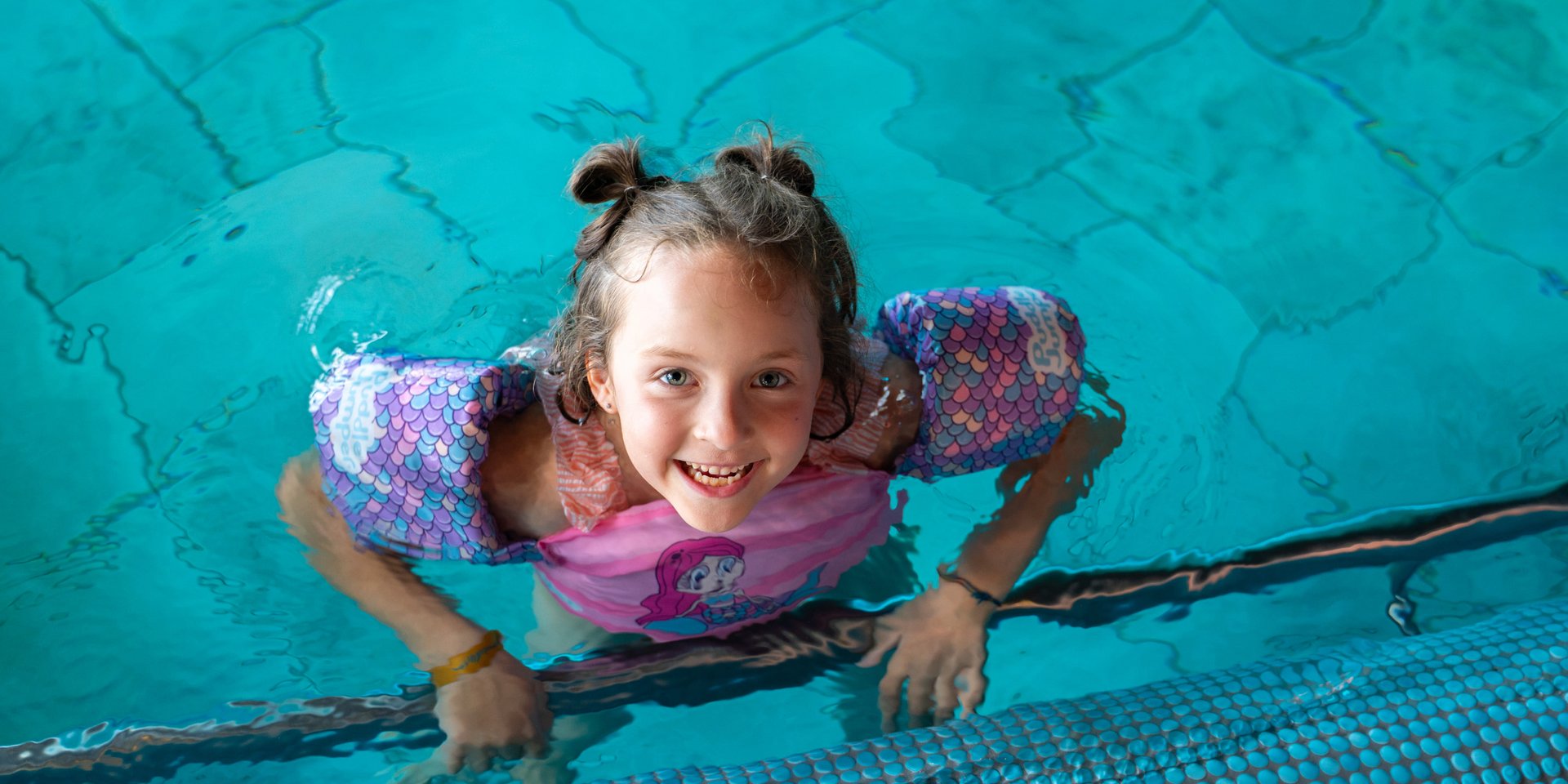 Ein Mädchen lacht vergnügt beim Planschen im Hallenbad des Hotels Vier Jahreszeiten am Schluchsee.