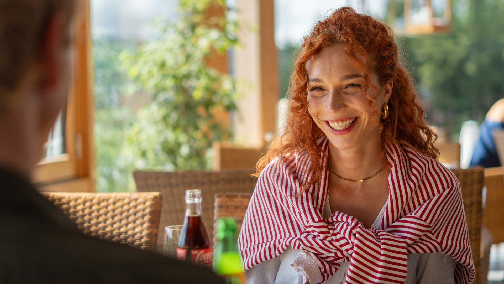 Lachendes Paar bei einer Erfrischung im hellen, holzverkleideten Café-Bereich.