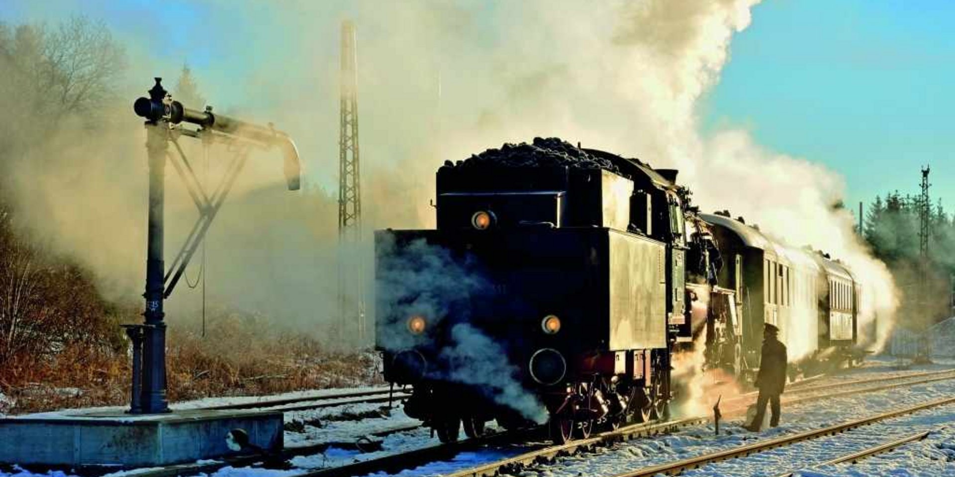 Eine Dampflokomotive bei der Fahrt durch eine winterlich verschneite Schwarzwald-Landschaft.
