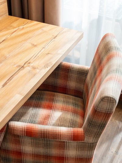 Schreibtisch aus Naturholz mit einem karierten Sessel in der Superior Suite Süd.