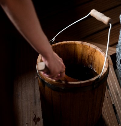 Vorbereitung für den Sauna-Aufguss: Ein klassischer Holzeimer mit Kelle steht bereit für die Gäste.