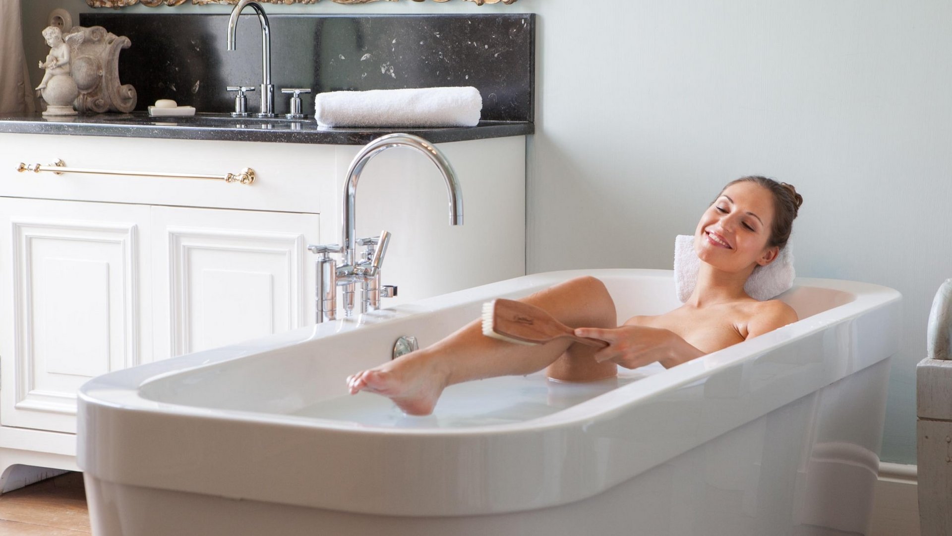 Eine Frau entspannt in einer modernen, weißen Badewanne in einem hellen Badezimmer.