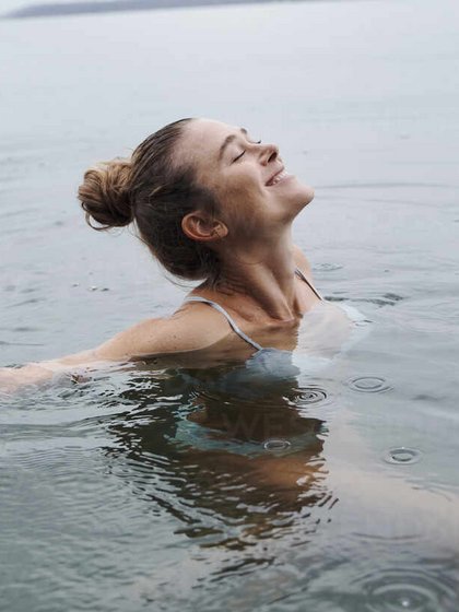 glueckliche-frau-mit-geschlossenen-augen-beim-schwimmen-im-see