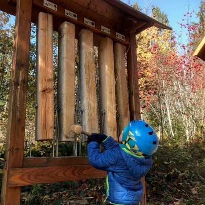 Kinder spielen an einer interaktiven Klangstation aus Holz im Naturpark Schlüwana.