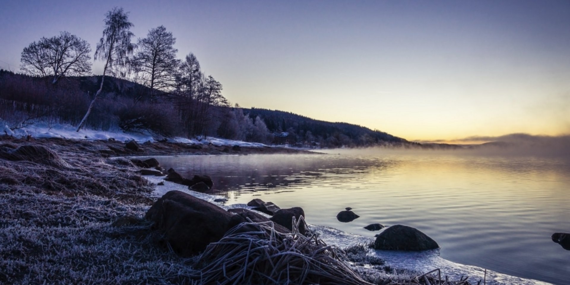 Die Abenddämmerung bricht über dem verschneiten Ufer des Schluchsees im Schwarzwald herein.