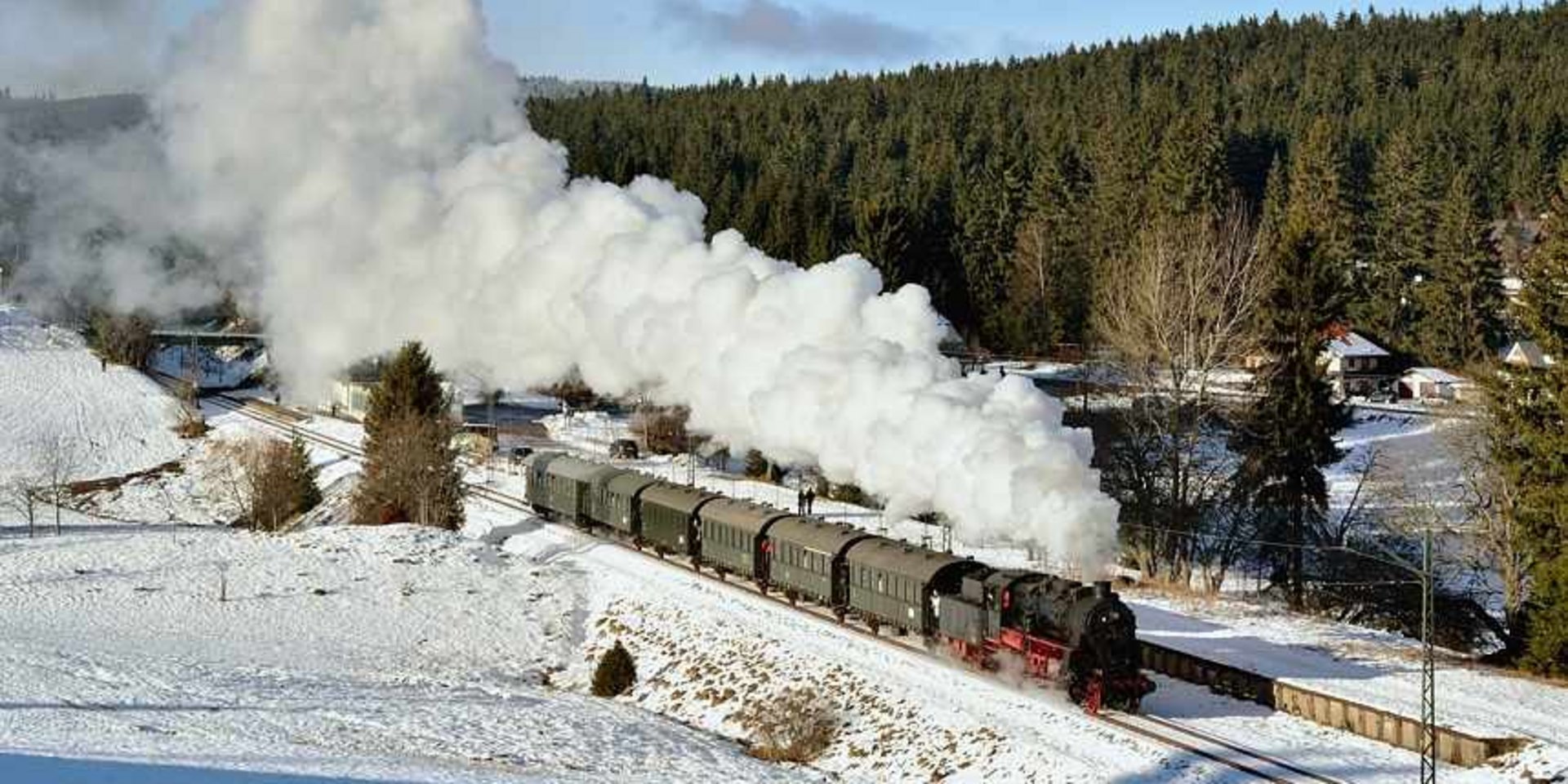 Winterliche Dampfzugfahrt: Eine historische Eisenbahn fährt durch den tiefen Schnee im Schwarzwald.