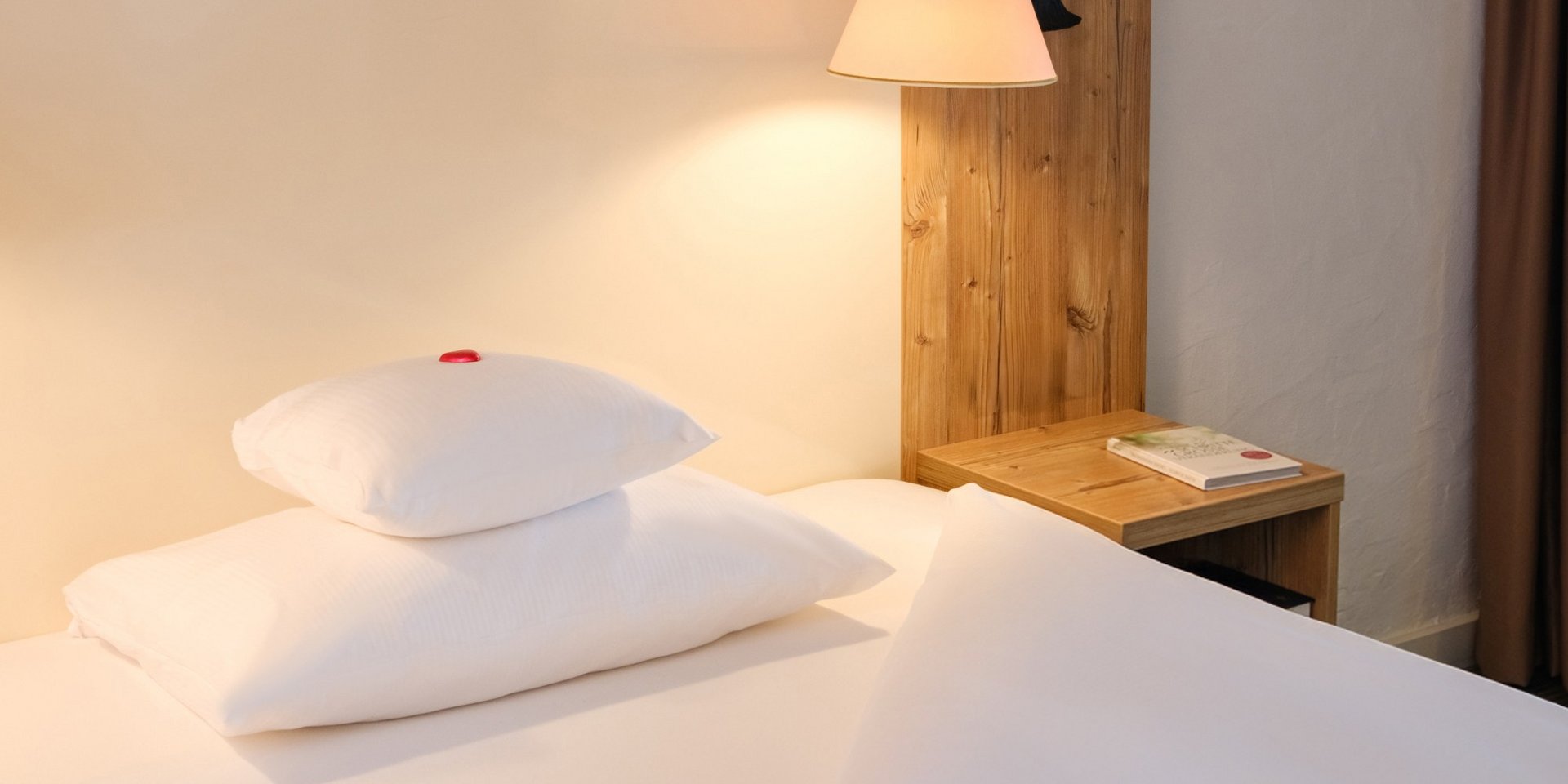 Komfortables Einzelbett mit hellem Holzkopfteil im Hotel Vier Jahreszeiten am Schluchsee.