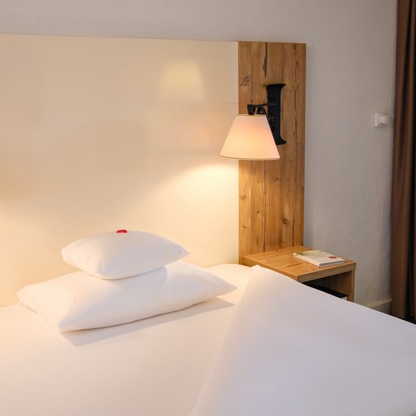 Komfortables Einzelbett mit hellem Holzkopfteil im Hotel Vier Jahreszeiten am Schluchsee.