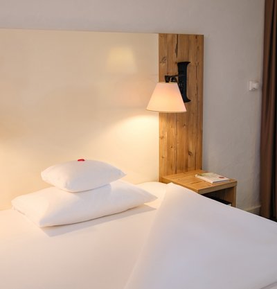 Komfortables Einzelbett mit hellem Holzkopfteil im Hotel Vier Jahreszeiten am Schluchsee.
