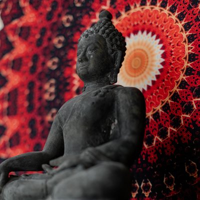 Detailaufnahme einer thailändischen Buddha-Statue vor einem farbenprächtigen, kreisförmigen Wandbehang im Hotel Vier Jahreszeiten.