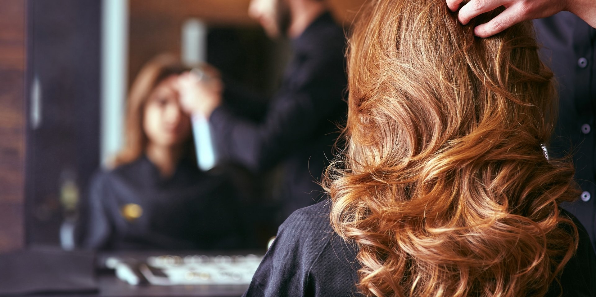 Blick über die Schulter einer Kundin auf das Haarstyling Friseursalon.
