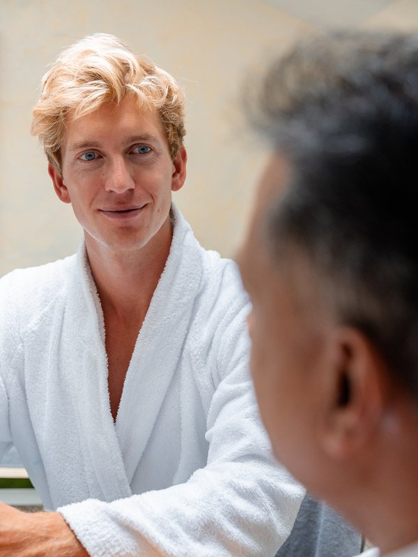 Ein Gast im weißen Bademantel während eines Beratungsgesprächs im Hotel Vier Jahreszeiten am Schluchsee.