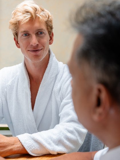 Ein Gast im weißen Bademantel während eines Beratungsgesprächs im Hotel Vier Jahreszeiten am Schluchsee.