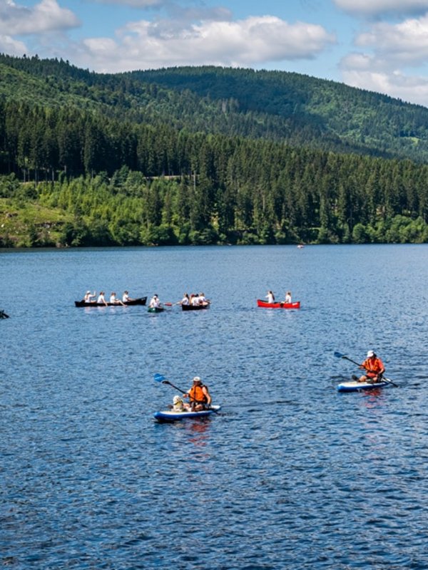 Kanufahrer und Wassersportler auf dem Schluchsee im Schwarzwald bei Sommerwetter.